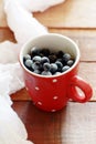 Frozen berries of black currant in a red mug on a wooden background. Sweet berry billet Royalty Free Stock Photo