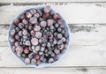 Frozen berries fruits background in ceramic plate close up.Fruits with frost. on vintage white wooden planks, blank space for text Royalty Free Stock Photo