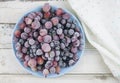 Frozen berries fruits background in ceramic plate close up.Fruits with frost. on vintage white wooden planks, blank space for text Royalty Free Stock Photo