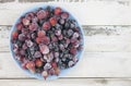 Frozen berries fruits background in ceramic plate close up.Fruits with frost. on vintage white wooden planks, blank space for text Royalty Free Stock Photo