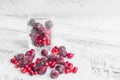 Frozen berries in a glass cup on the light wooden background. Cherry and cranberry