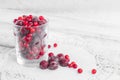 Frozen berries in a glass cup on the light wooden background. Cherry and cranberry