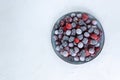Frozen berries in a gray plate on a white background.
