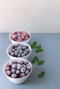 Frozen berries in a white bowls on a gray background.