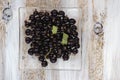 Frozen black currant on glass plate and white painted wooden background.