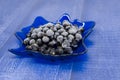 Frozen blackcurrant berries lie on blue glass plate in the form of a tree leaf Royalty Free Stock Photo