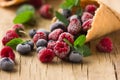 Frozen blueberries berries raspberries in a waffle cone, fresh cherries on old wooden table - right side view Royalty Free Stock Photo