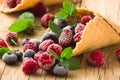 Frozen blueberries berries raspberries in a waffle cone, fresh cherries on old wooden table - right side view Royalty Free Stock Photo