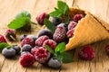 Frozen blueberries berries raspberries in a waffle cone, fresh cherries on old wooden table - right side view Royalty Free Stock Photo