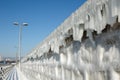 Frozen breakwater with icicles against blue sky