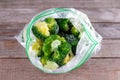 Frozen broccoli in a plastic bag on wooden table. Selective focus Royalty Free Stock Photo