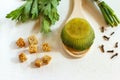 Frozen broth briquette with herbs and vegetables on a wooden spoon, horizontal frame on a white background