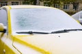 Frozen yellow car covered snow at winter day, view front window windshield and hood. Royalty Free Stock Photo