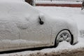 Frozen car covered snow in winter day, view side window on snowy forest background Royalty Free Stock Photo