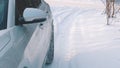 Frozen car driving carefuly on the snow covered road. Close up on the mirror and tires