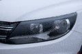 Frozen car headlights with icicles and snow in winter season Car side mirror covered with ice