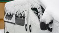 Frozen car, white minivan covered snow at winter day. Urban scene of city life in winter time in snow storm