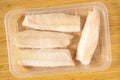Frozen cod fish loins in vacuum package on the cutting board. Top view