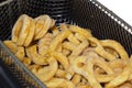 Frozen curly fries, coated in herbs and spices, cooking in a deep fat fryer basket.