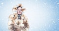 Frozen cute young girl in a red fox fur coat warming hands, cold, snow, on blue background with snow. Royalty Free Stock Photo