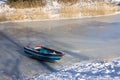 Frozen ditch with wooden row-boat lying on the ice