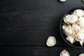 Frozen dumplings tortellini and ravioli in black bowl  on black wooden table background   top view flat lay   with copyspace and Royalty Free Stock Photo