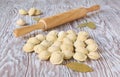 Frozen dumplings and wooden rolling pin on a wooden table