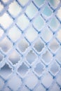 Frozen fence made of metal mesh covered with snowy hoarfrost, winter day. Winter snow texture. Royalty Free Stock Photo