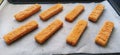 Frozen fish sticks are laid out on baking paper. Cooking a fish delicacy. Baking paper on a baking sheet. A quick lunch Royalty Free Stock Photo