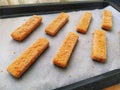 Frozen fish sticks are laid out on baking paper. Cooking a fish delicacy. Baking paper on a baking sheet. A quick lunch Royalty Free Stock Photo