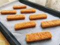 Frozen fish sticks are laid out on baking paper. Cooking a fish delicacy. Baking paper on a baking sheet. A quick lunch Royalty Free Stock Photo