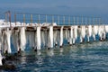 Frozen fishing pier with hanging icicles in a sunny winter day