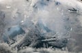 Beautiful view of icy and foggy glass with beautiful snow patterns and blue background in cold winter