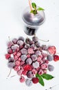 Frozen forest berries and cocktail in ice cubes on wooden table background. Royalty Free Stock Photo