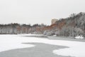 A frozen forest after a snowfall in winter on an iced pond. A yellow tall building on the background Royalty Free Stock Photo