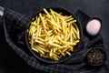 Frozen French fries in a frying pan. Black background. Top view