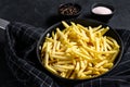 Frozen French fries in a frying pan. Black background. Top view