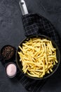 Frozen French fries in a frying pan. Black background. Top view. Space for text