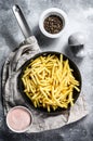 Frozen French fries in a frying pan. Gray background. Top view