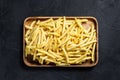 Frozen French fries in a wooden bowl. organic potatoes. Black background. Top view