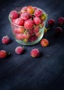 Frozen and fresh berries in a glass pial on a black background. Royalty Free Stock Photo