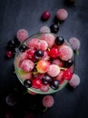 Frozen and fresh berries in a glass pial on a black background. Royalty Free Stock Photo