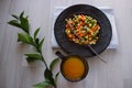 Frozen fried vegetables on black plate. Vegan breakfast with juice. Vegetables food mix on white wooden background with plant Royalty Free Stock Photo