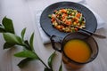 Frozen fried vegetables on black plate. Vegan breakfast with juice. Vegetables food mix on white wooden background with plant Royalty Free Stock Photo