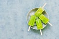 Frozen fruit kiwi juice in a bowl with ice against a blue background . A refreshing Popsicle on a stick. Green frozen juice on a s Royalty Free Stock Photo