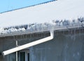 Frozen gutters damage. House roof covered snow, icicles and frozen roof gutter with downspout pipe Royalty Free Stock Photo