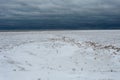 Frozen ice and sand creating a cliff face with crack down the middle on Lake Michigan on gloomy overcast day