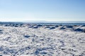 Frozen ice, snow, and sand dunes on beach with hills in distance Royalty Free Stock Photo