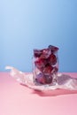 Frozen icy red berries in a glass on crumpled wrapping paper sta