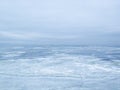 A frozen icy river and a cloudy sky in a single color connected on the horizon line.